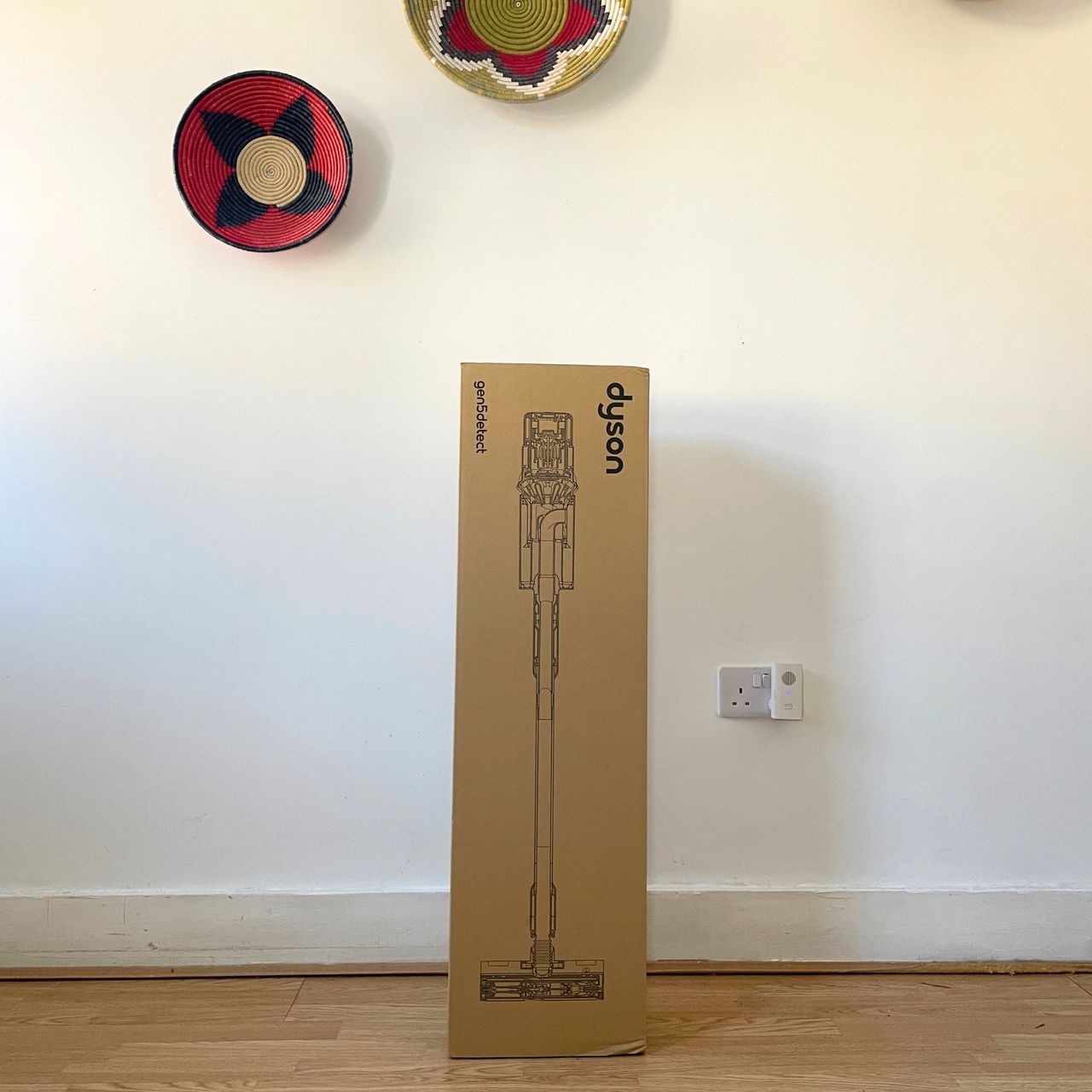 Dyson Gen5detect box sitting on wooden floor in front of a white wall