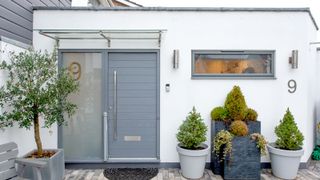 Contemporary grey composite door agaisnt white wall with plants in foreground