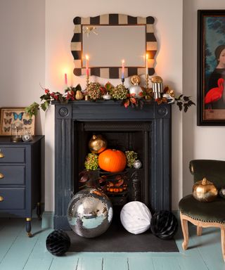 living room with Halloween decor around fireplace and mantel, mirror, aqua painted floor boards, dresser, chair, candles