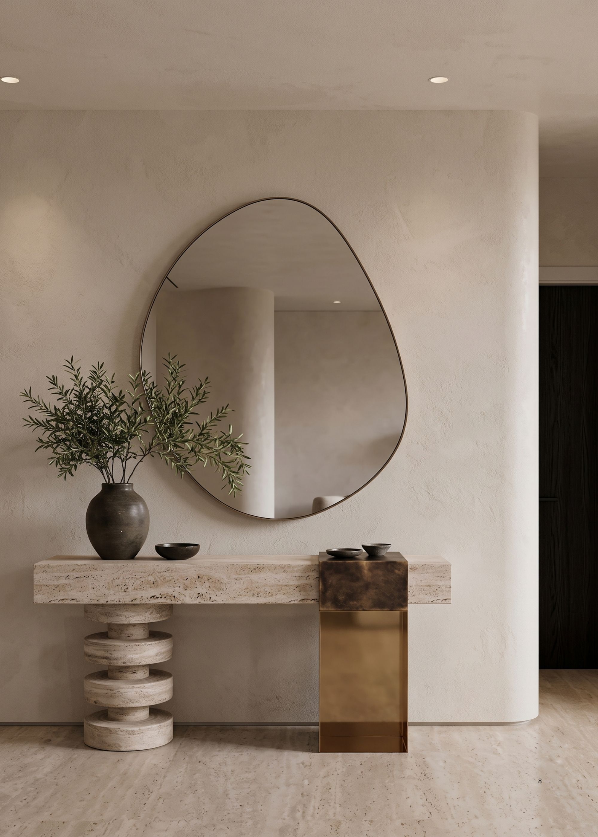 Image of a white limewash wall with a marble console that has an abstract mirror over it and a black vase filled with stems.