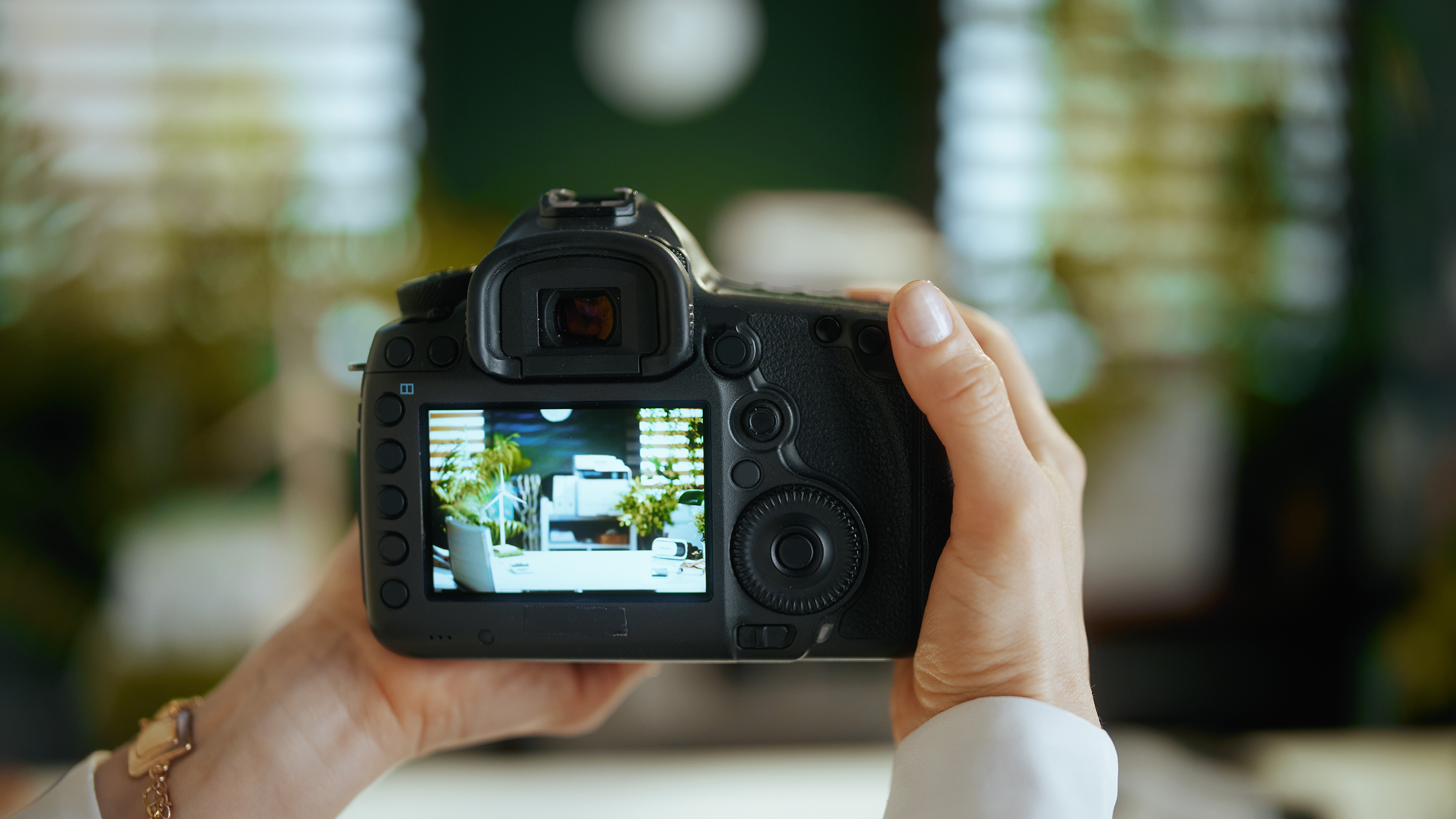 Closeup on woman real estate agent in green office in white blouse with dslr photo camera making interior photo.