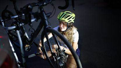 Woman sitting with bicycle and car bicycle rack at the night 