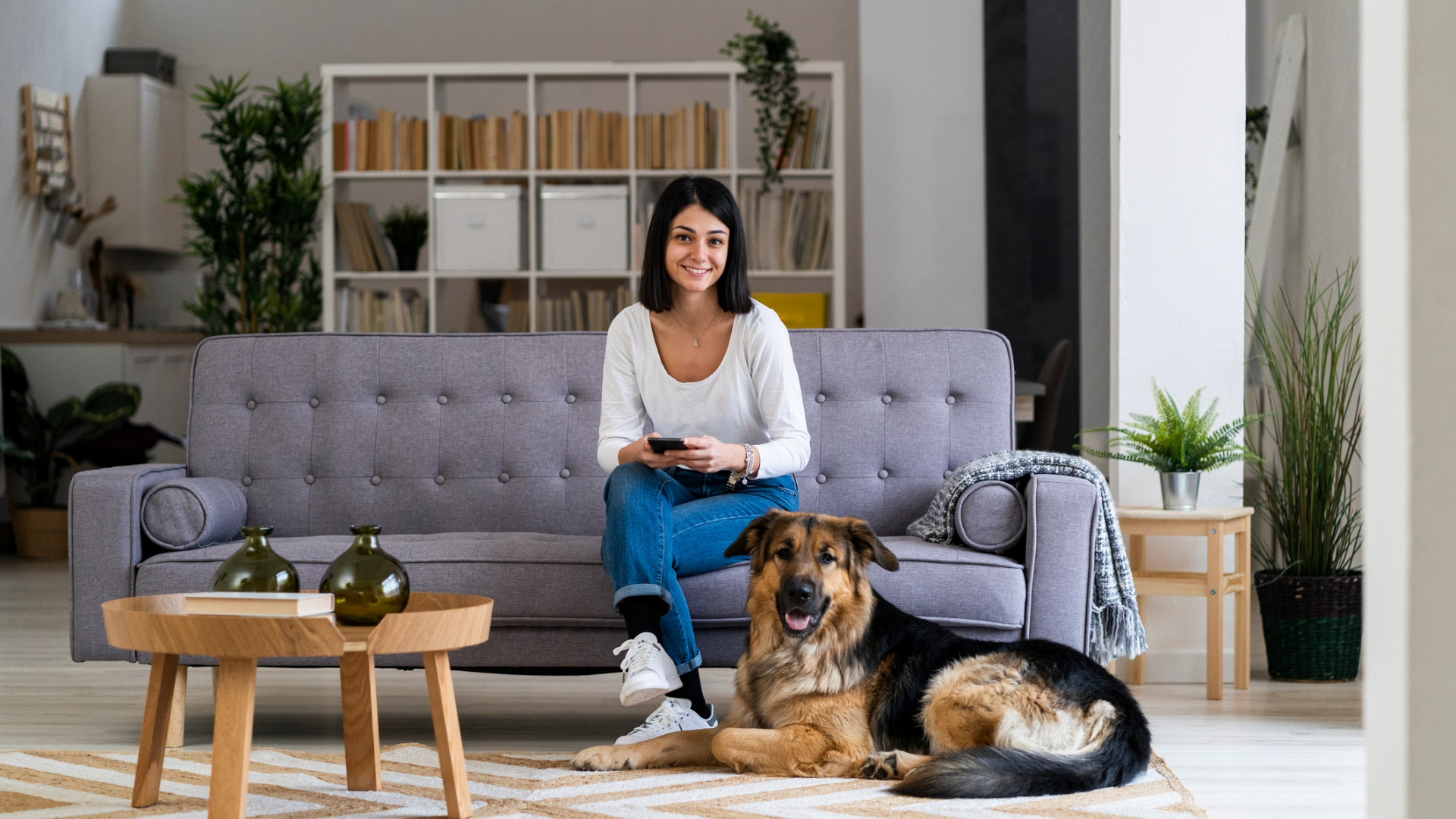 smiling woman sitting on the couch sits with her dog