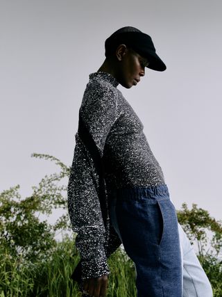 Woman in sparkly knitwear jumper and cap with plants