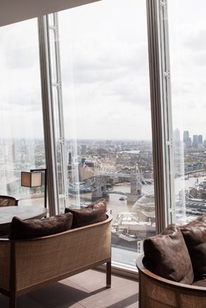 Oblix, London, UK. Wooden sofas next to large windows with a view of the city below.