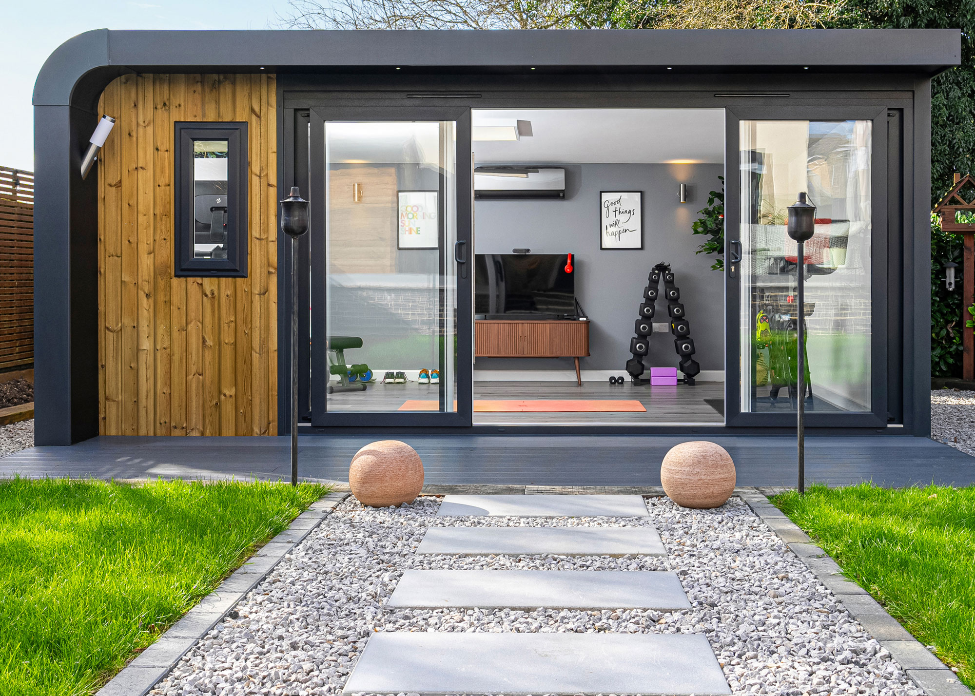 gym in modern garden room with equipment, gravel, stone and lawn landscaping