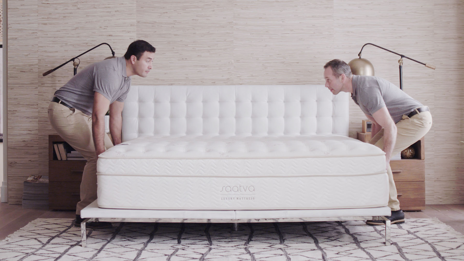 Two delivery men place a classic Saatva mattress under the bed frame