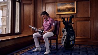 Cameron Smith sitting on a chair looking at the claret jug trophy