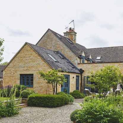 exterior of extended stone cotswold cottage with landscaped garden and gravel driveway