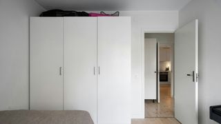 a white warrobe in a white bedroom with light brown wooden flooring