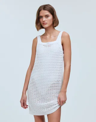 model wears open knit dress over white one-piece swim suit 