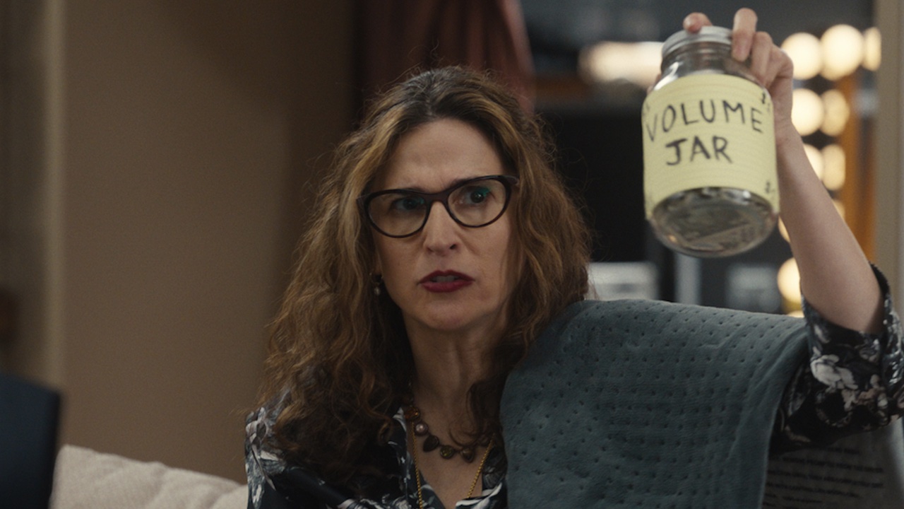 Stacy holding up the Volume Jar of money in Hacks Season 4