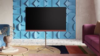 Loewe We.SEE TV with coral red soundbar on a stand, in a classy living room