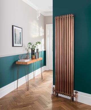 A tall and narrow copper radiator in hallway