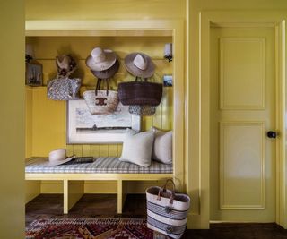 mud room with yellow lacquered walls and hats and bags and bench seat