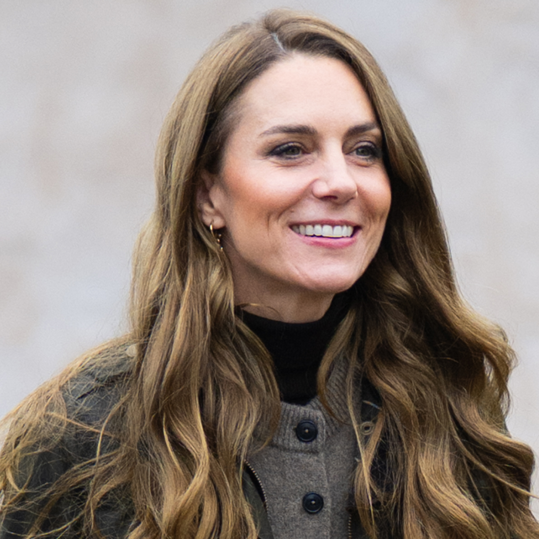 Kate Middleton wearing a brown cardigan and smiling