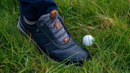 golfer kicking a golf ball into a better lie