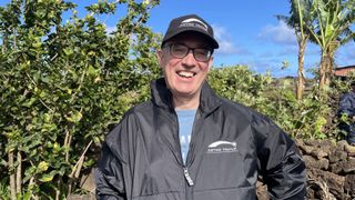 Mike Frost wears a black jacket and black hat and smiles at the camera.