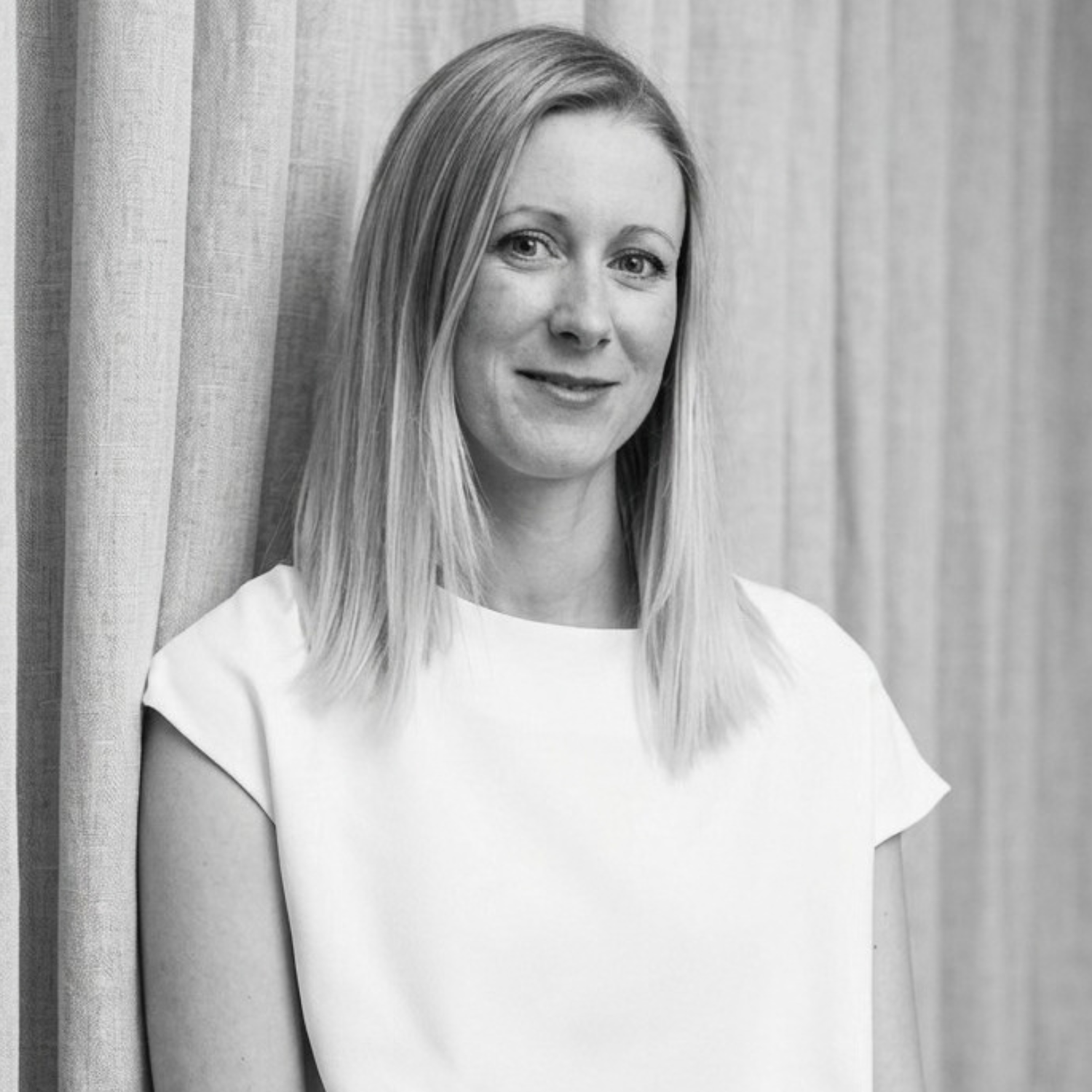 A black-and-white photo of a woman in a white top with shoulder-length blonde hair