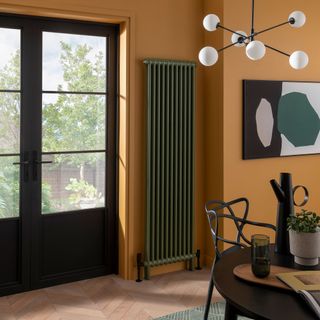 Tall green painted radiator on yellow wall of dining space