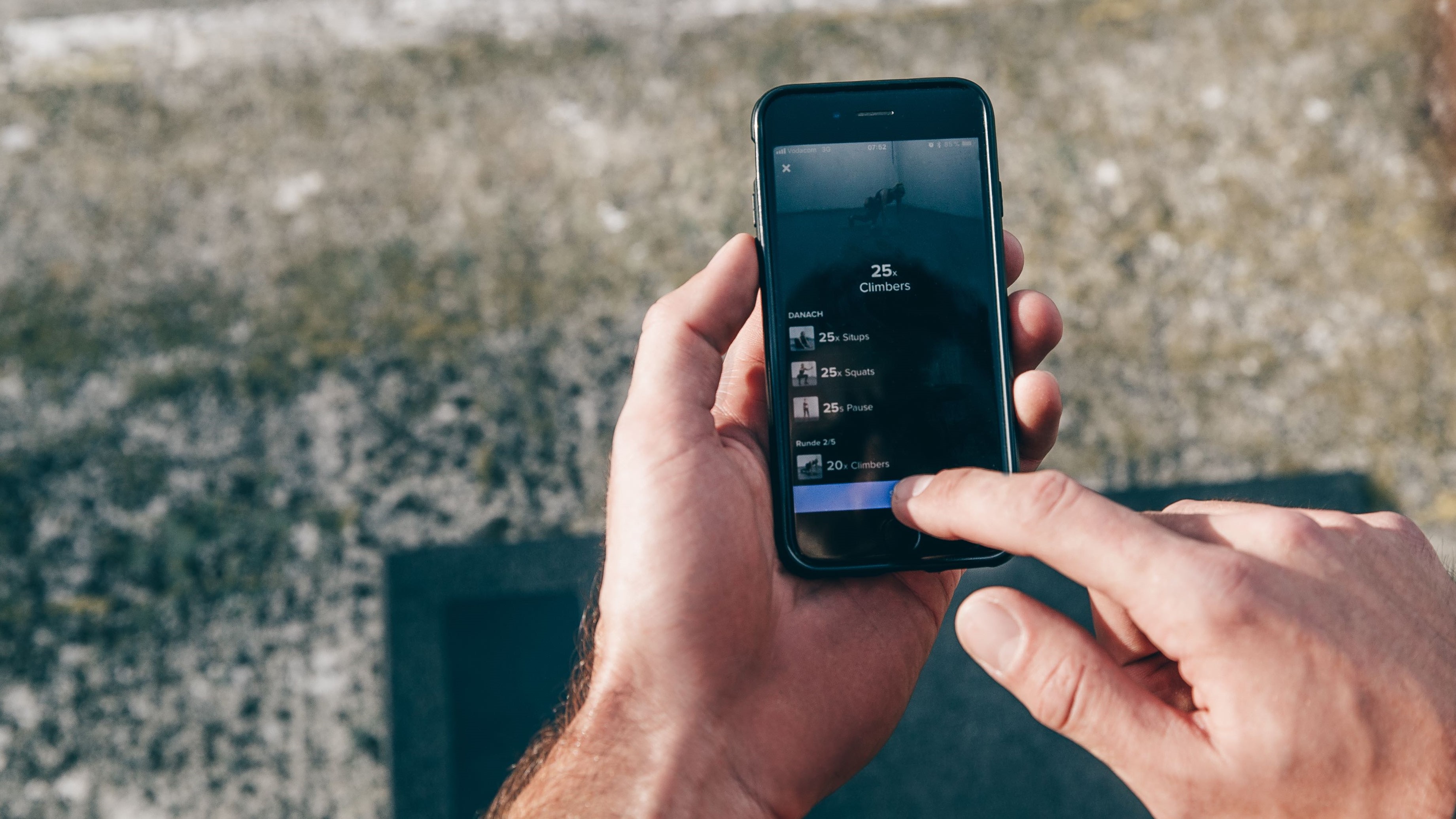En mand sidder og swiper sig igennem Freeletics-menuen på sin mobil