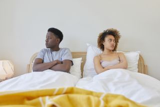 A couple facing away from each other in bed