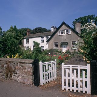 exterior of house with white fence and flowering plant