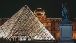 A photo of the Louvre Museum Pyramid lit up at night.