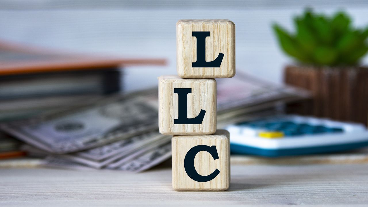 Three stacked wooden blocks spell out the initials LLC. 