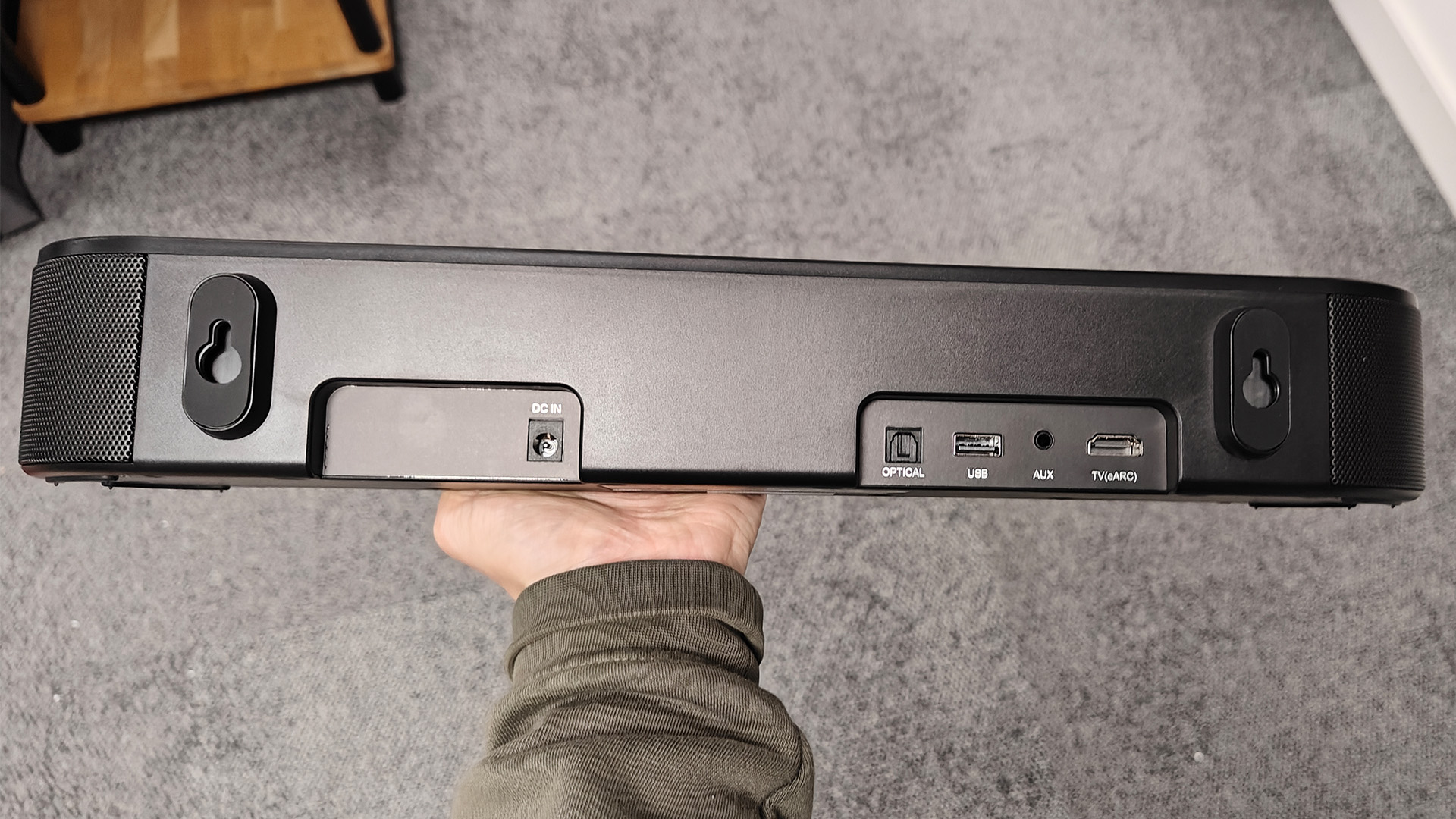 Majority Bowfell Halo Atmos soundbar system, soundbar held in hand showing rear of unit and connections