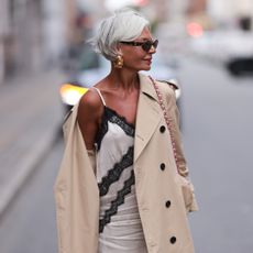 Best concealer for mature skin - Grece Ghanem wearing tinted glasses, slip dress and beige trench coat