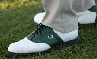 Detail of a Masters logo on an Augusta member's green and white golf shoes