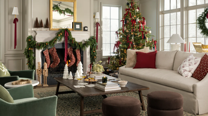 a living room decorated for Christmas with a tree, garland over the mantel, and lots of decorative objects around the room
