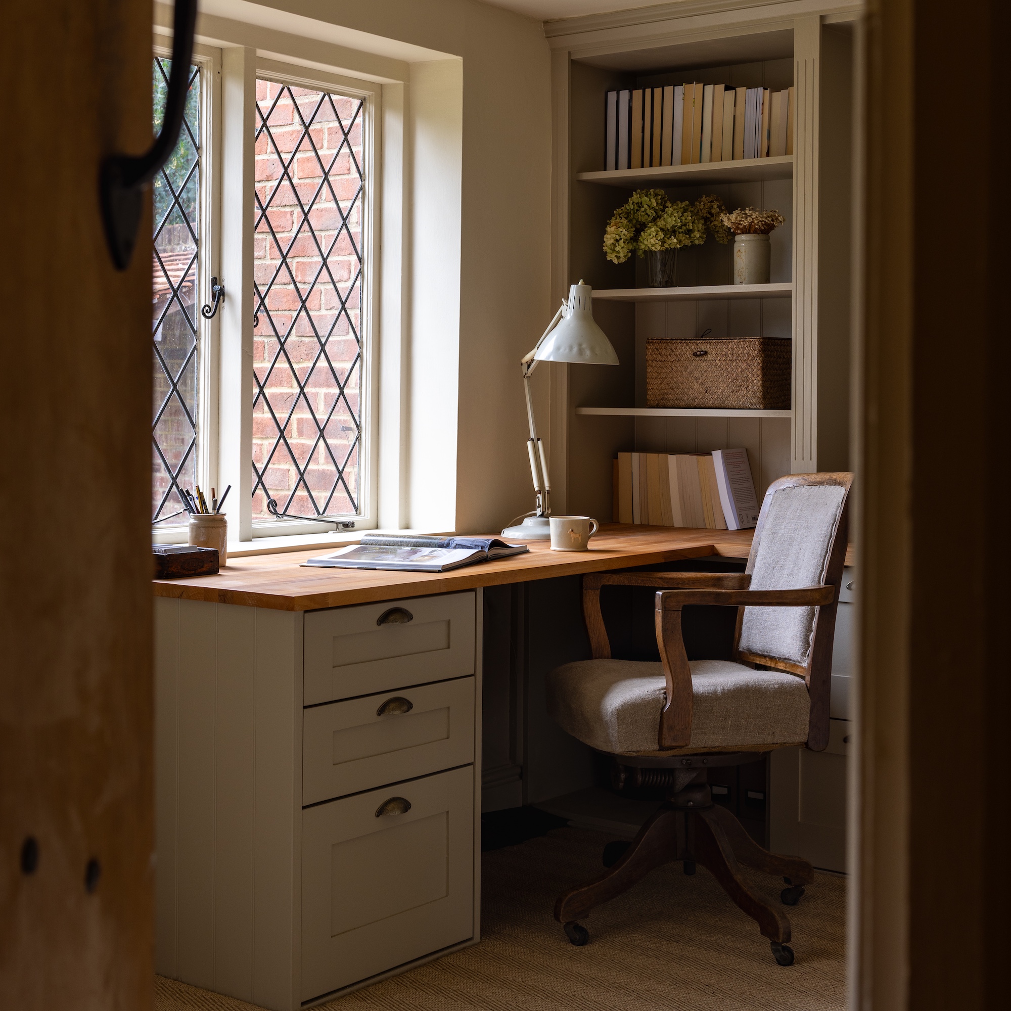small home office with leaded window, desk and chair and bespoke fitted shelves