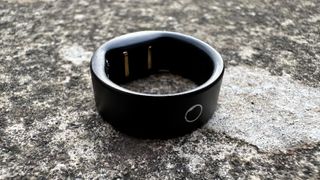 The Circular Ring Slim in black against a concrete surface.