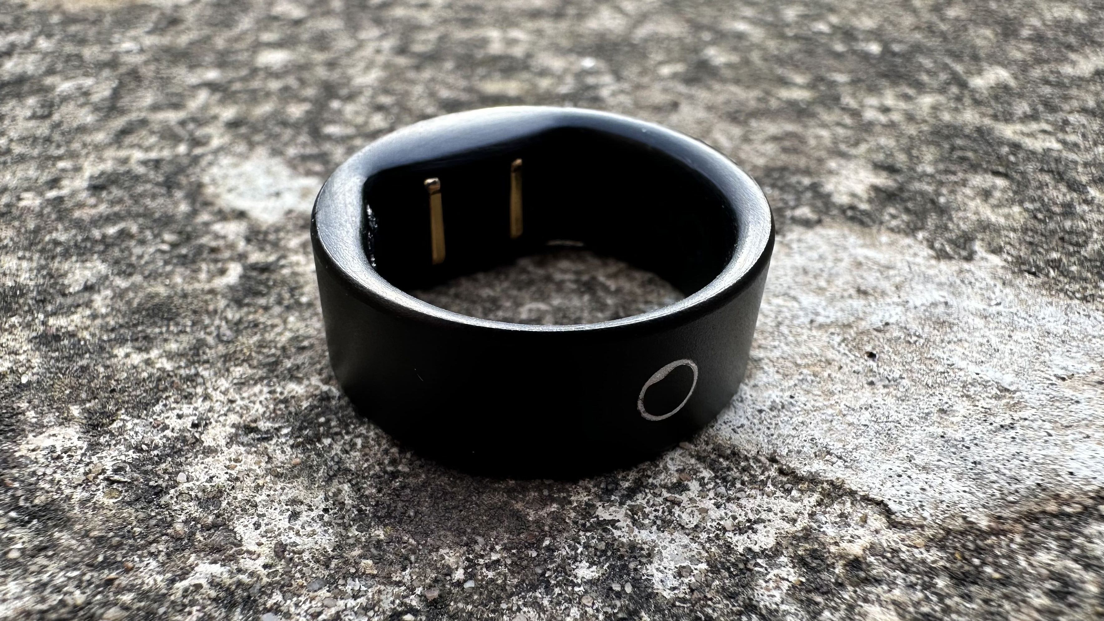 The Circular Ring Slim in black against a concrete surface.