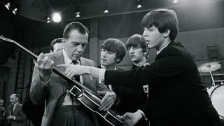 Television host Ed Sullivan receives some guitar lessons from Beatle Paul McCartney in between rehearsals at CBS television studios in Manhattan, where the English rock 'n' roll sensations will make their nationwide television performance debut February 9th. Fellow Beatles John Lennon and Ringo Starr stand behind