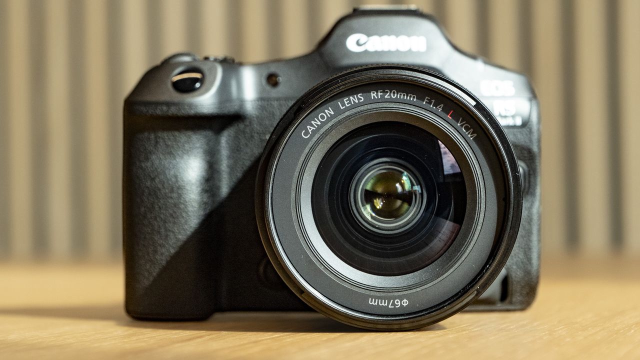 Canon RF 20mm F1.4L VCM lens on a wooden table, attached to the EOS R5 Mark II camera