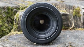 The Nikon Nikkor Z MC 105mm f/2.8 VR S lens sitting on a rock