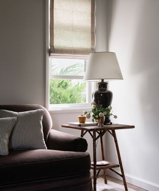 living room corner with dark brown sofa, window and side table with dark brown lamp