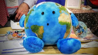 The new Celestial Buddies plush toy – Our Precious Planet – is on display at the New York Toy Fair. The company's older model, Earth, sits on a shelf to the left, along with other plush toy planets.