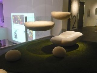 A mound of artificial grass with cloud-shaped seating suspended above