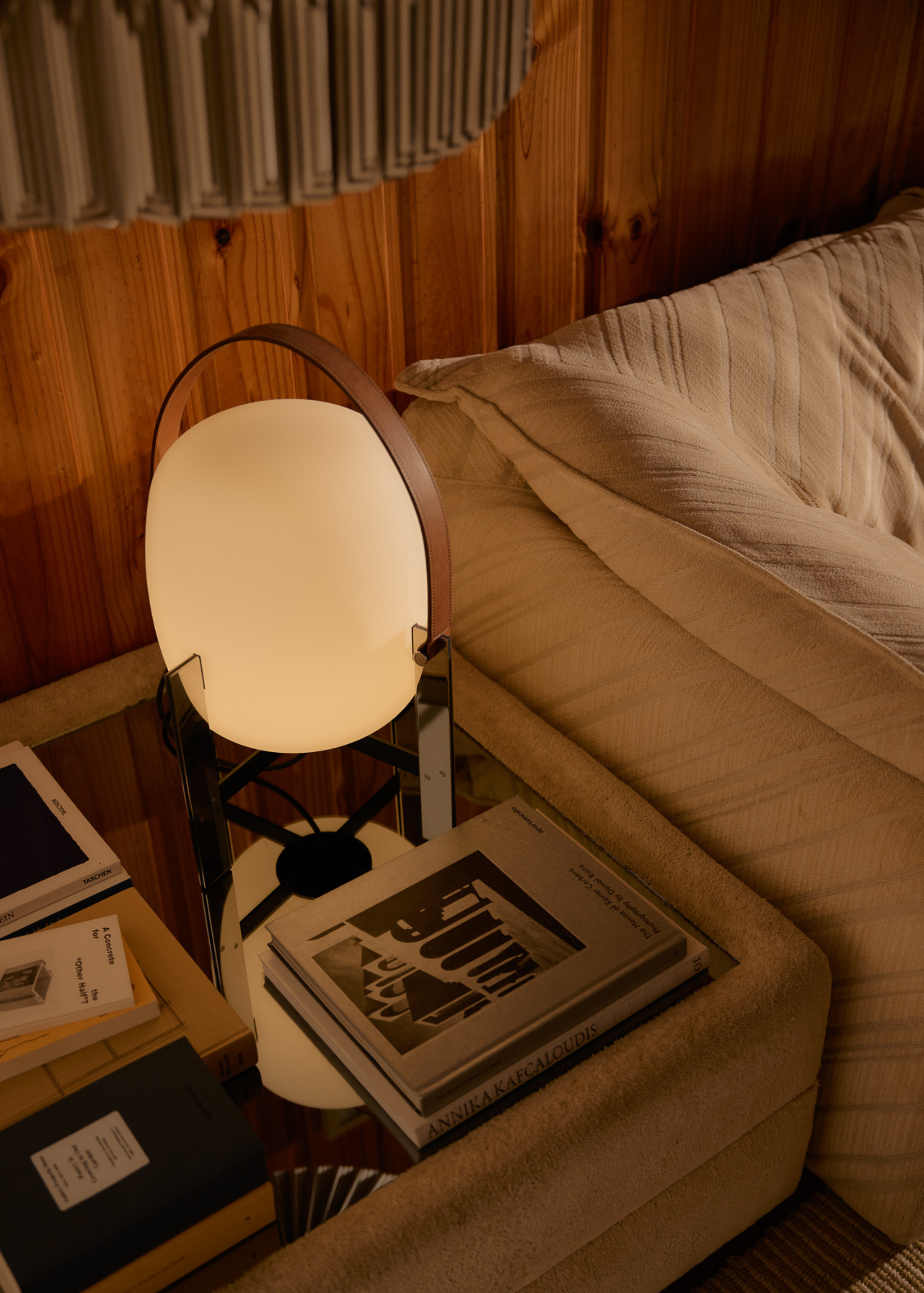 A bedside table with a mirrored top, a small lamp, a set of books, and a box