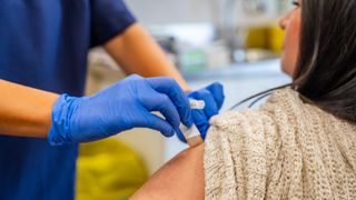 a doctor puts a bandaid on a woman&#039;s shoulder after she&#039;s gotten a shot