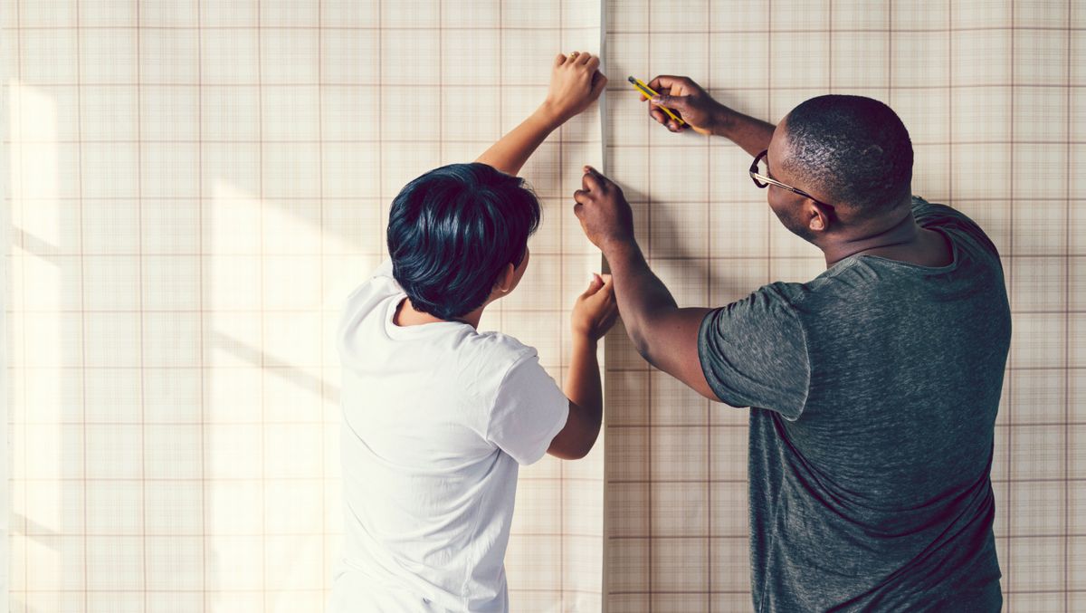 Couple wallpapering a wall together