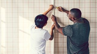 Couple wallpapering a wall together