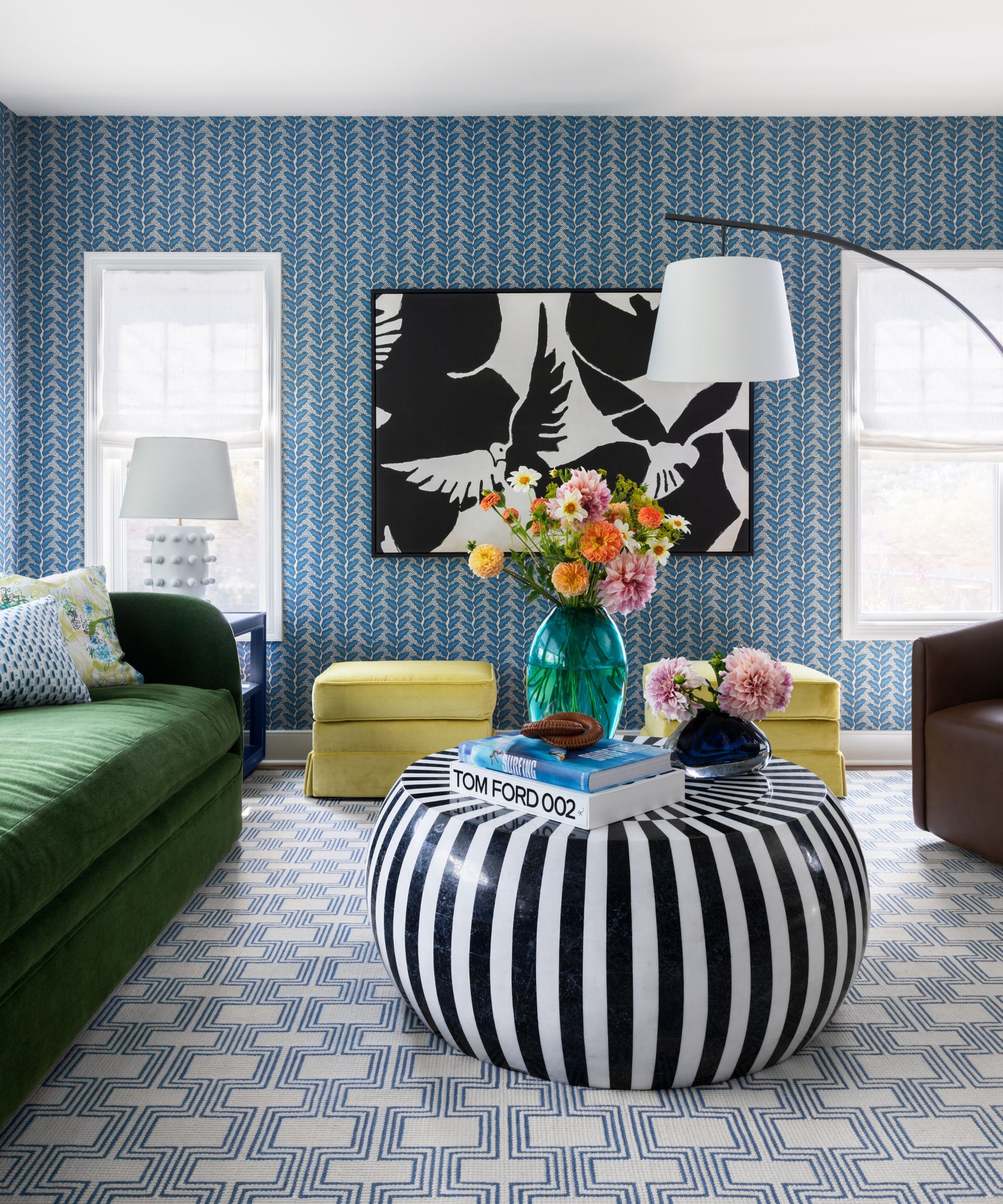 Living room with blue wallpaper, green couch, striped coffee table and statement rug