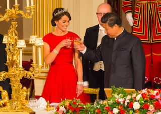 Kate Middleton wearing a red gown and diamond tiara and clinking wine glasses with Chinese president Xi Jinping at a banquet