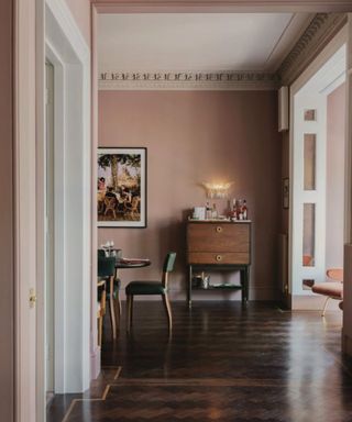 Dark parquet flooring in an open-plan dining area and hallway painted pink