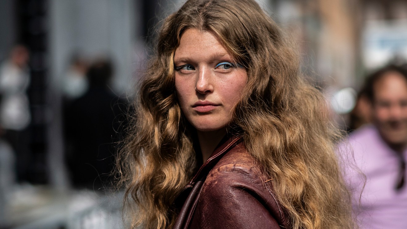 A model with curly, freshly cleaned hair standing in the street.
